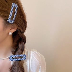Close-up of blue plaid fabric hair clips and pearl jewelry worn on braided hair
