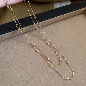 Detailed close-up of golden rice bead chain necklace showing high-gloss metallic finish