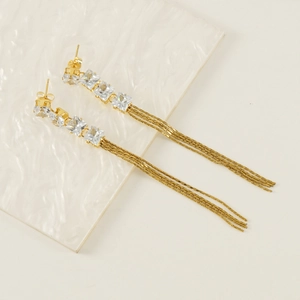 Detail view of gold tassel earrings with square cubic zirconia and fine chain fringe