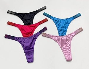 Close-up of colorful thong underwear with luxury rhinestone waist straps on silk fabric