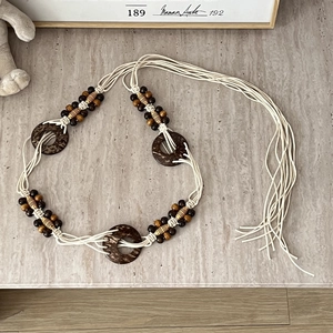 Detail of bohemian braided waist belt with beige cotton cords and wooden beads on marble