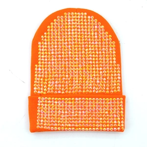 Dettaglio del berretto arancione in acrilico con strass lucidi e risvolto in maglia