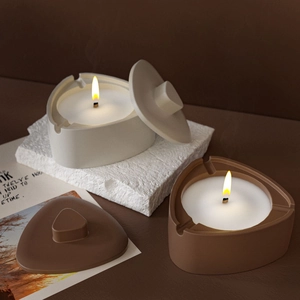 Bougies parfumées triangulaires minimalistes avec couvercles crème et mocha sur pierre