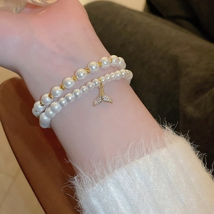 Detailed close-up of double-layer pearl bracelet with a sparkling zircon fishtail charm