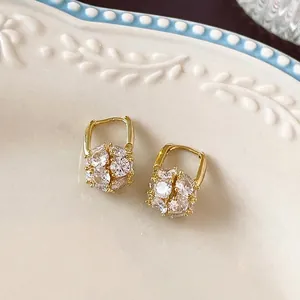Elegant gold-plated hoop earrings with sparkling zircon sphere charms on ceramic plate