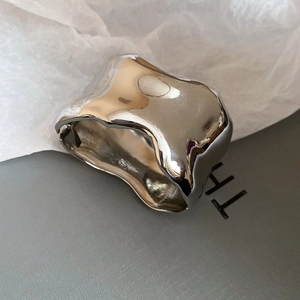 Detail of an irregular silver wide cuff bracelet with a high-polished liquid metal finish
