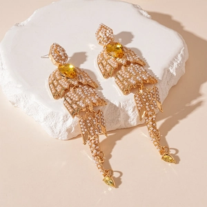 Close-up of vintage gold drop earrings featuring white pearls and yellow gemstones