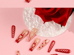 Macro shot of long coffin fake nails with red heart patterns and glitter flame designs
