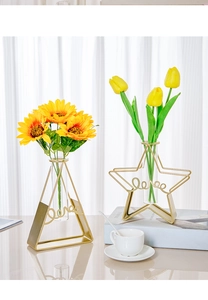 Golden geometric iron vases with 'love' lettering and glass tubes on white tabletop