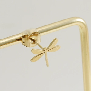 Macro shot of a gold-plated stainless steel dragonfly stud earring on a jewelry stand