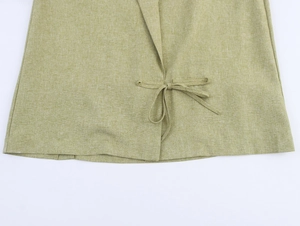 Close-up of light green linen fabric featuring a side tie-up bow detail and texture