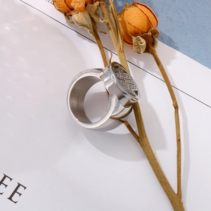 Macro detail of a wide silver metal ring with a round seal engraving on white card