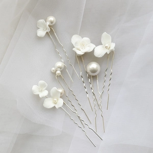 Detail of bridal hair pins with ceramic flowers and pearls on white soft tulle fabric