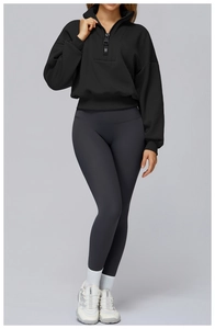 Detail view of woman's black quarter-zip sweatshirt and charcoal high-waisted leggings