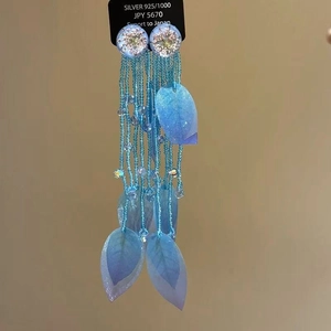 Detail of blue bead tassel earrings with silver posts and leaf charms on product card
