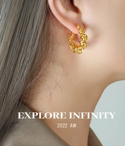 Close-up of twisted gold C-shape earrings in PVD plated steel with infinity engraving