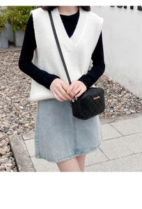 Outdoor shot of a black quilted crossbody bag with metal logo and chain strap