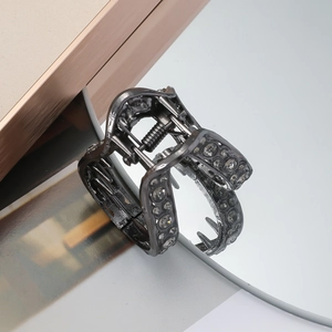Detailed close-up of dark grey V-shaped hair claw clip with sparkling rhinestones