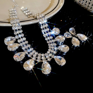 Macro shot of silver teardrop tassel jewelry set with sparkling crystals on black background