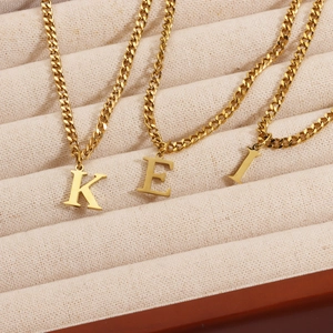 Detailed view of 18K gold plated initial pendants K E L on classic curb chains