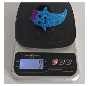 Detail shot showing 9g weight of blue sequined ghost hair clip on digital scale