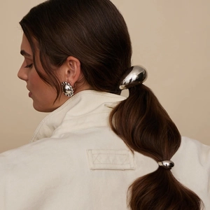 Silver stainless steel ponytail cuff and matching earrings set worn by a fashion model