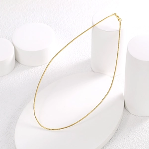 Minimalist gold thin collar necklace displayed on elegant white geometric props