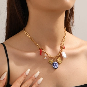 Detail of gold chain necklace with red chili, pearl, heart lock, and seashell pendants