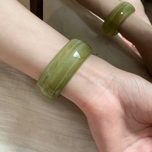 Detail of wide translucent green resin bracelet with natural texture on female wrist