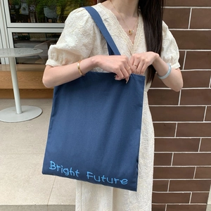 Bolso tote de lona azul con estampado Bright Future en una elegante escena de cafetería