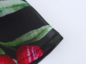 Detail of sheer black mesh fabric featuring vibrant red cherry prints and neat stitching