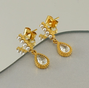 Detail of gold water drop zircon earrings with pearls reflected in a round mirror