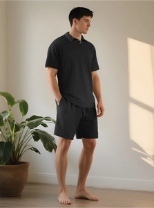 Dettaglio del set polo e pantaloncini neri in maglia con fine trama verticale