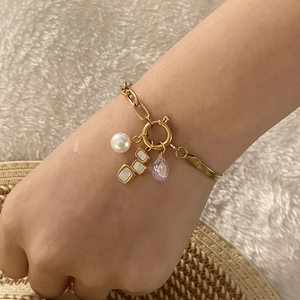 Bracciale dorato con perle e cristallo viola con catene metalliche asimmetriche