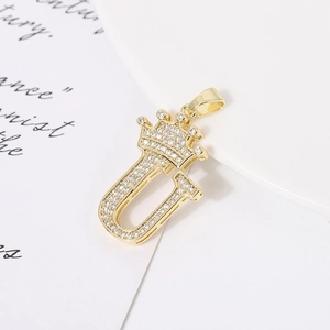 Macro shot of gold-plated crown letter U pendant with shimmering cubic zirconia inlay