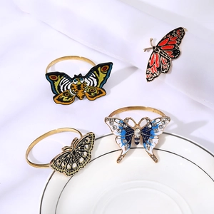 Close-up of golden butterfly napkin rings with colorful enamel and rhinestone details