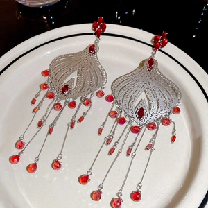 Macro detail of silver vintage teardrop tassel earrings with red crystals and carvings