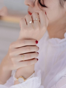 Close-up of elegant gold flower and pearl rings worn by model for a minimalist style