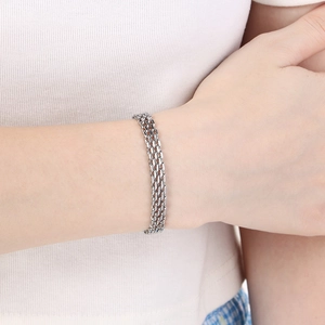 Three-strand silver titanium steel woven bracelet displayed on a woman's wrist