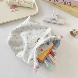 Detailed shot of floral drawstring storage bag with blue flower patterns and pens