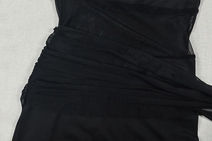 Detailed view of sheer black mesh fabric with intricate ruched pleats and layered texture