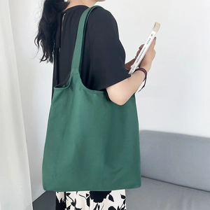 Detail view of large dark green canvas tote bag with thick handles and open-top design