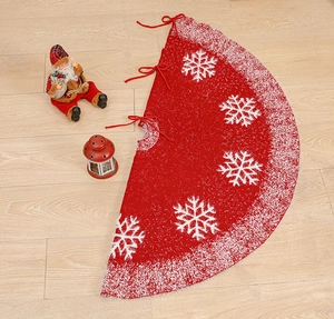 Close-up of red knitted Christmas tree skirt with white snowflakes and faux fur trim