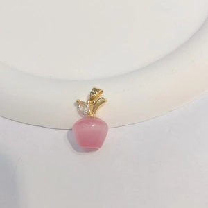 Detail of pink cat-eye stone apple pendant with 18k gold leaf and crystals