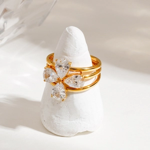 Three-layer gold stainless steel ring with pear-shaped zirconia clover on a white base