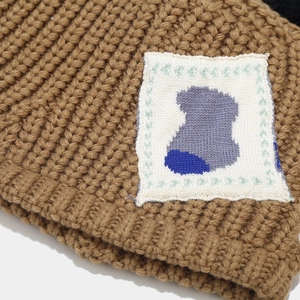 Macro shot of thick camel knit fabric and minimalist patch on a winter bucket hat
