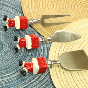 Three-piece Santa chimney cheese knife set with red brick resin handles on blue placemat