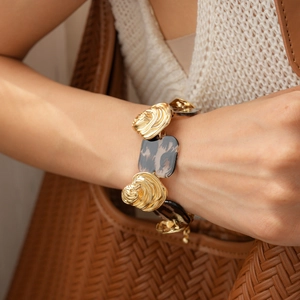 Close-up of golden wavy metal and leopard resin link bracelet on model wrist