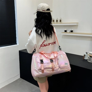 Pink pearlescent waterproof travel bag shown with shoulder strap on a model background