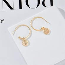 Detail shot of gold-plated hoop earrings with hollow floral pendants on white display card
